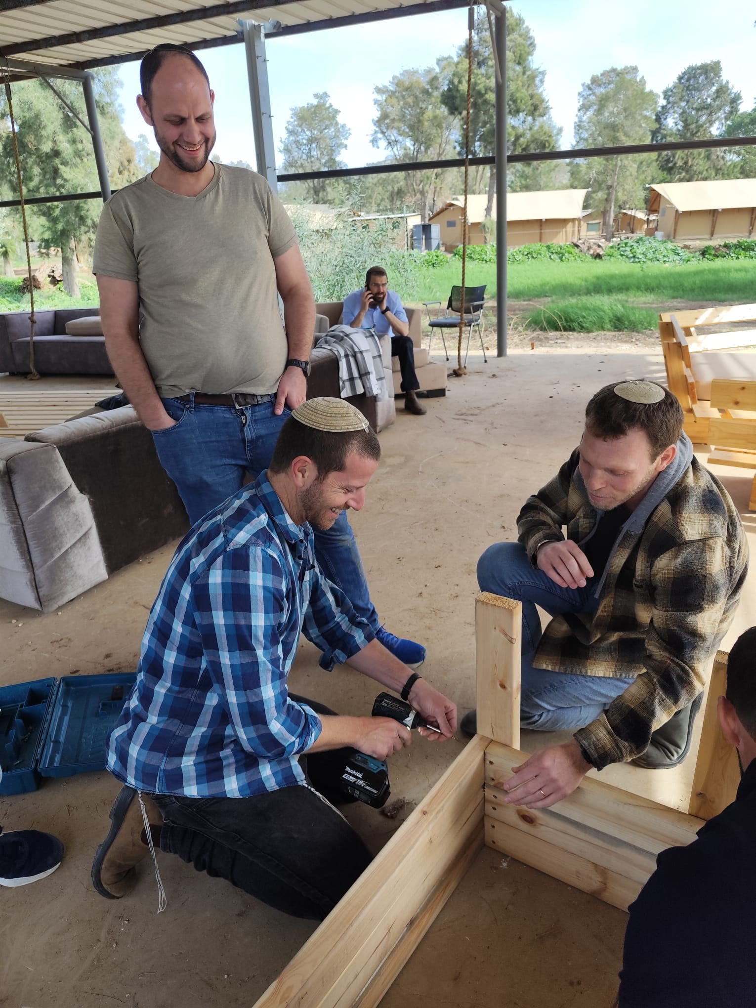 Men woodworking together under the outdoor pergola